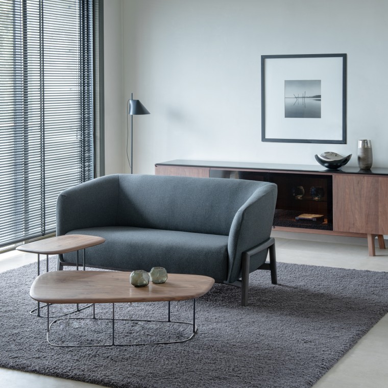 A two-seater sofa with two coffee tables in front of it. They are on the gray rug.