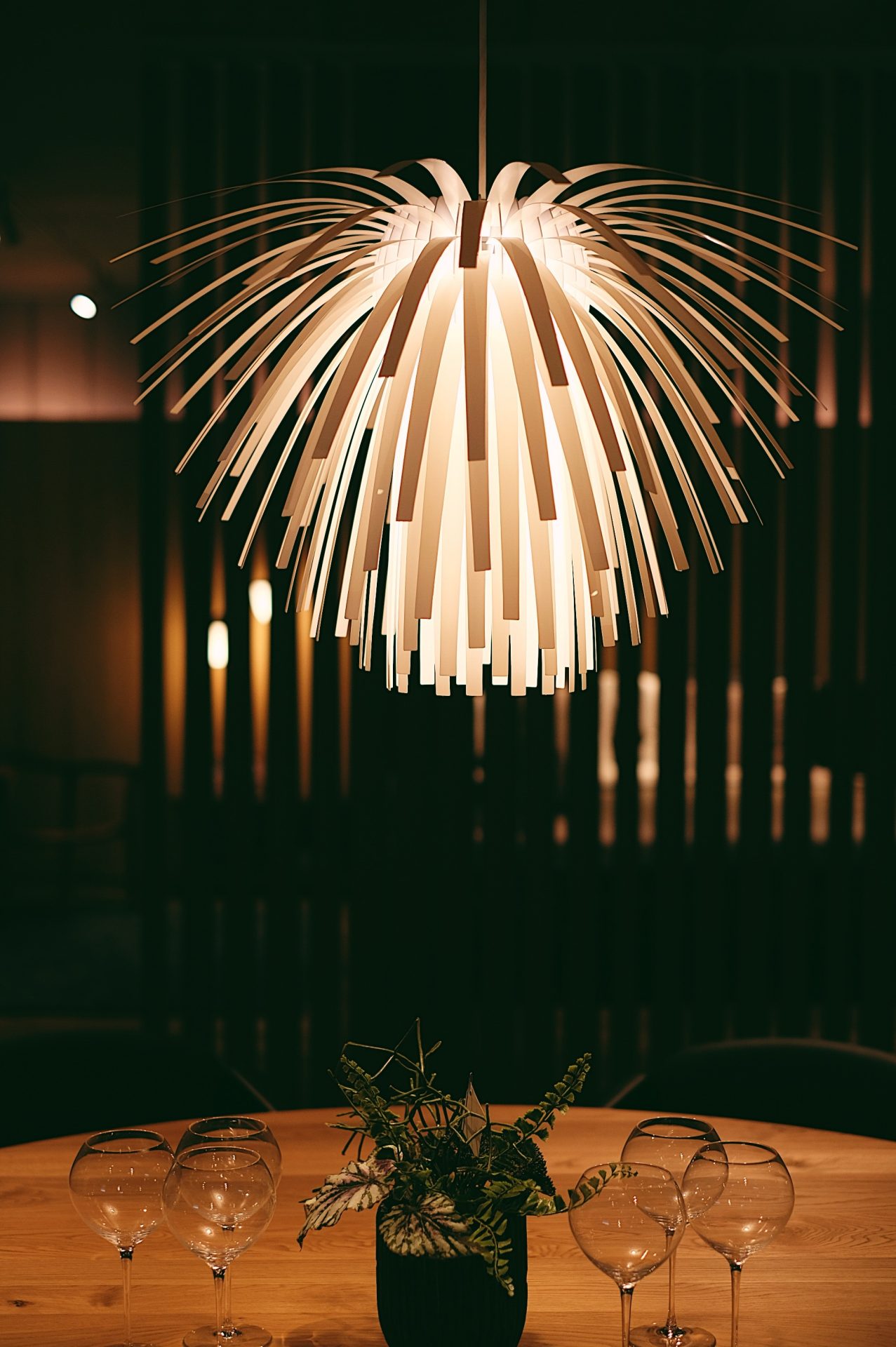 A round dining table displayed in our shop. A light with complex design above the table is focused.