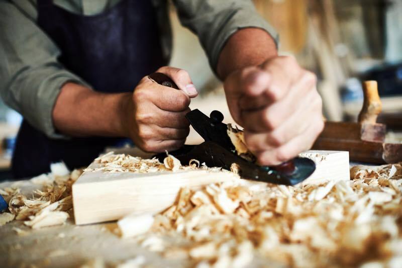 A scene of furniture making. Our craftsman is planing a wood piece.