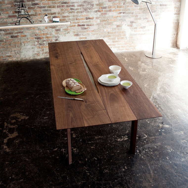 A dining table made of four pieces of wood planks. Some tea cups and bread are on it.