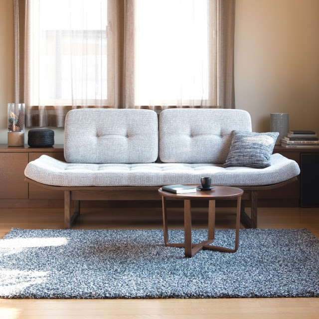 A bench or a sofa upholstered with gray fabric. There's a coffee table in front of it.