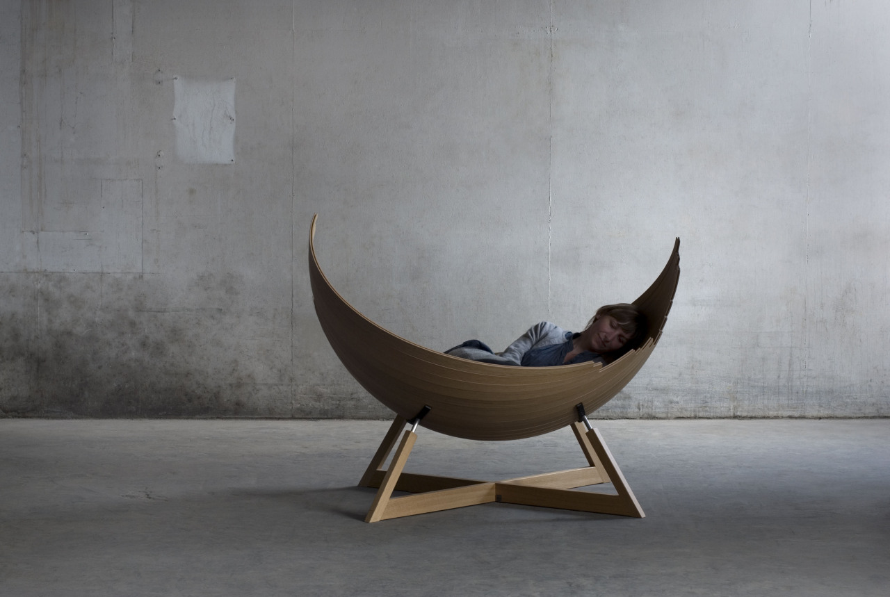 A woman is lying in the lounge chair. The chair looks like a cradle.