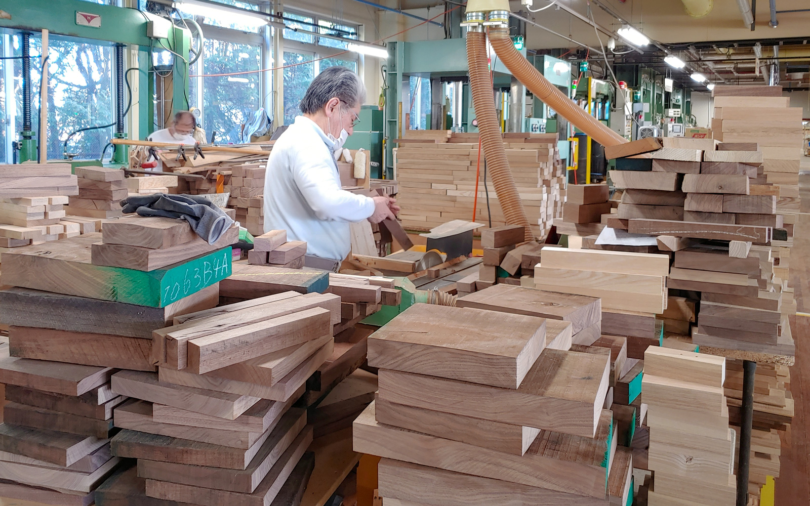 Our craftsperson is shaping and joining wood pieces to make wood boards.