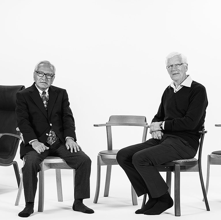 A black and white image. There are some chairs, and our founder and a designer sit next to each other.