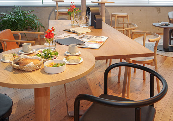 A round table in front and a square table in the back. There are some dishes on the round table.