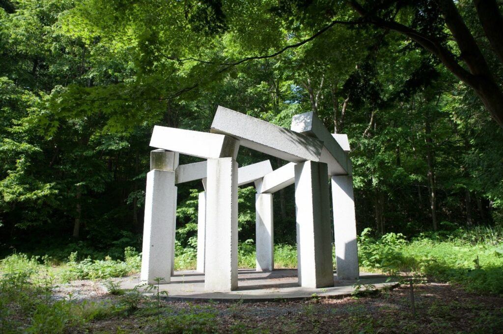 The image of a monument made of concrete blocks. It's a monument built in the company's forest.