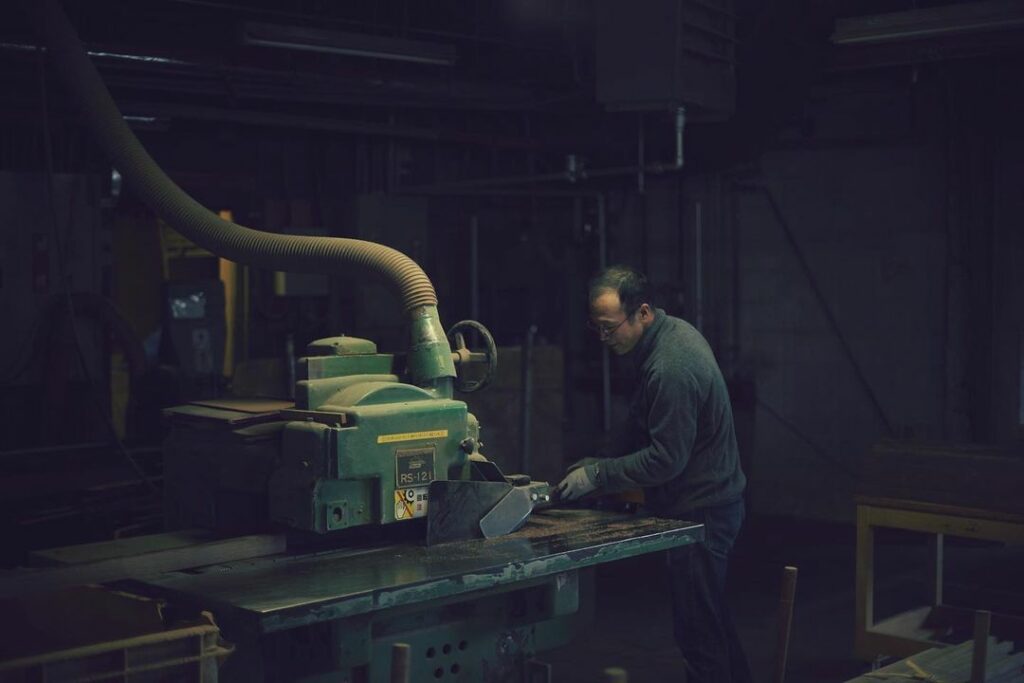 A furniture craftsman is working with an old machine.