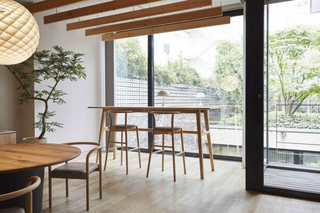 A high table with two high chairs by the window. The glass area is wide, and a lot of sun light is shedding inside.