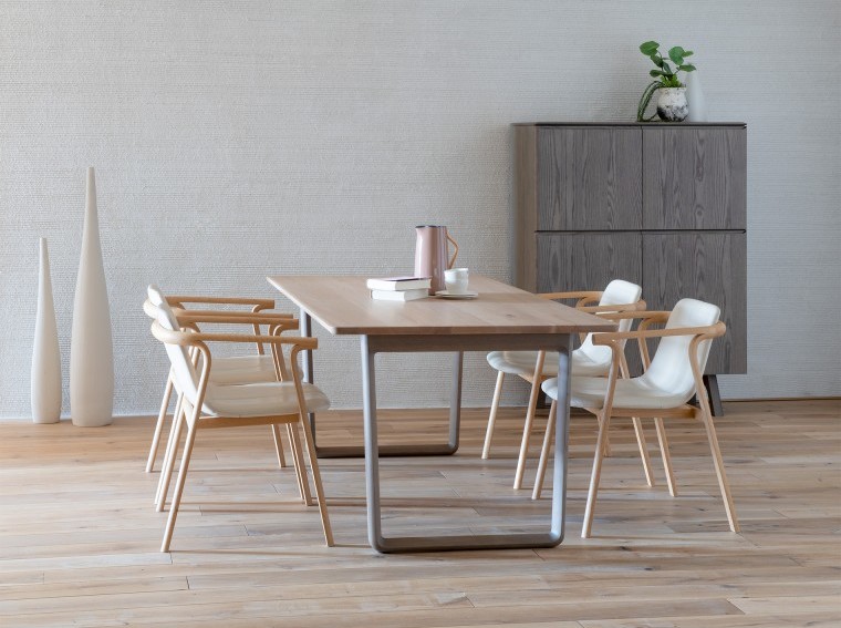 A dining set: a dining table of a natural color tabletop and gray legs; four dining chairs upholstered with white leather.