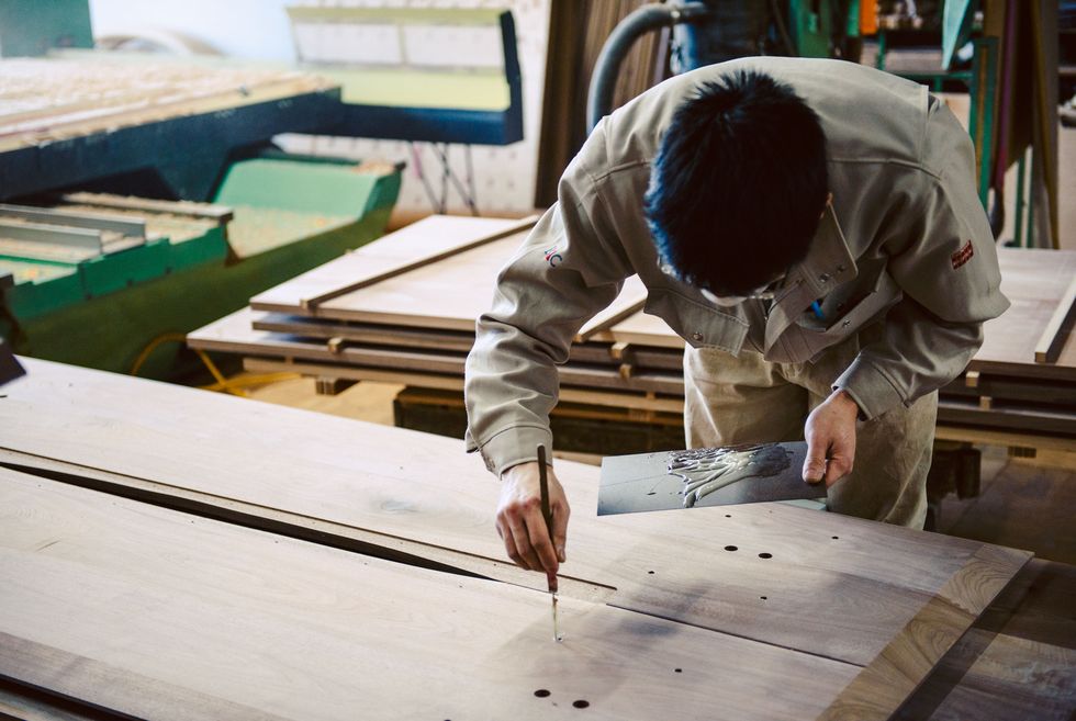 Our craftsperson is filling glue in the screw holes on the backside of a dining table.