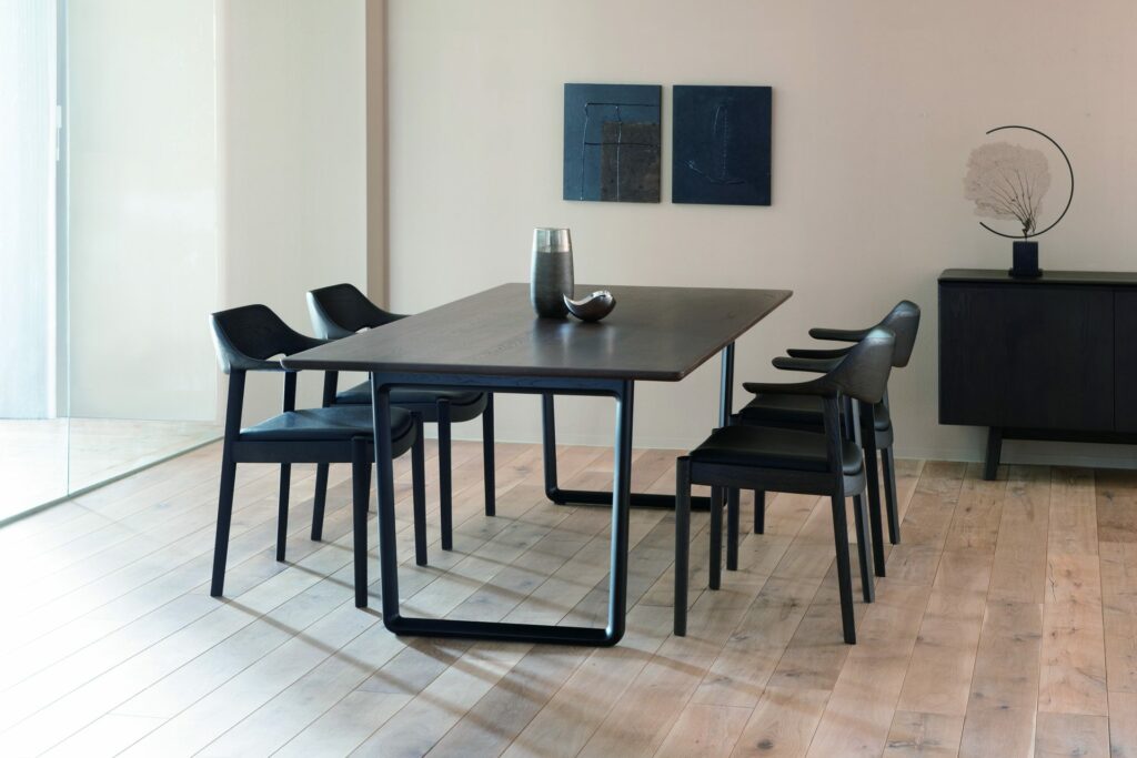 A dining table and four dining chairs. The wood and upholstery leather, everything is in black.