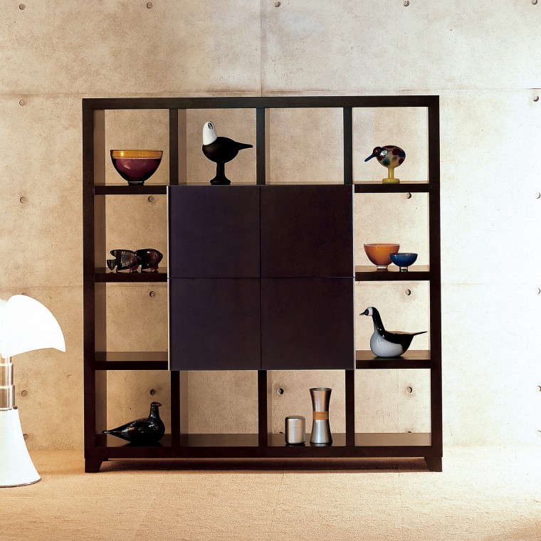 A wooden shelf with 16 compartments, 4 of which has doors. Some small objects are displayed.