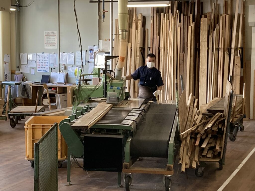 A craftsman is milling wood, checking the details of wood, such as grain, density, etc.