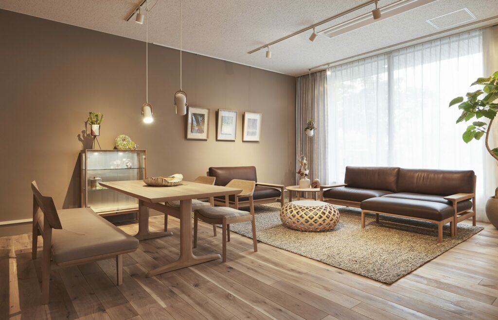 A part of a furniture shop where a bench, a dining table, two dining chairs, and a sofa set can be seen.