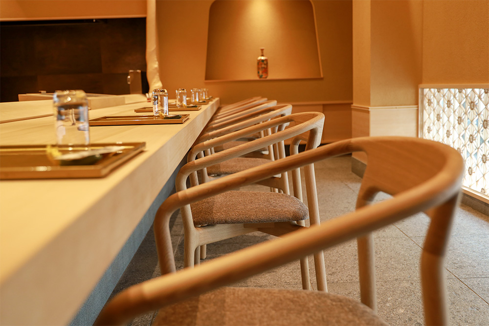 Wooden dining chairs lined up along the counter table of a classy Japanese restaurant.