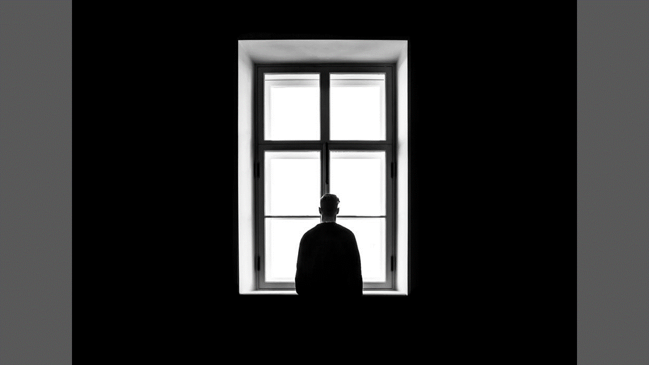 A guy is standing by the window. Because of the light from the window, the figure is completely darkened.