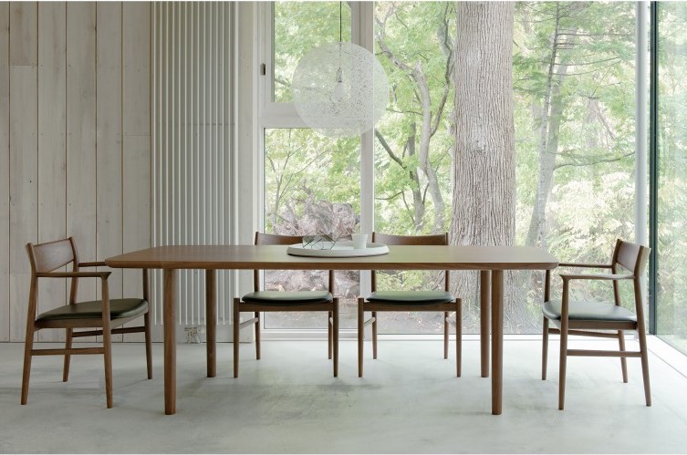 A wooden dining table with four wooden chairs by the big window. On the table is a white porcelain plate. Besides, a Mayuhana lamp is hang over the table.