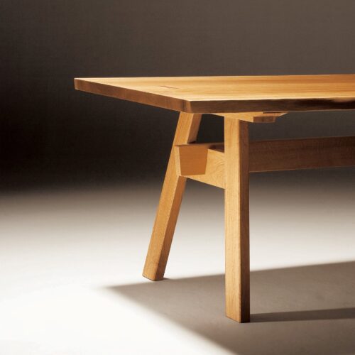 A partial image of a wooden table with one of the turret-shape legs