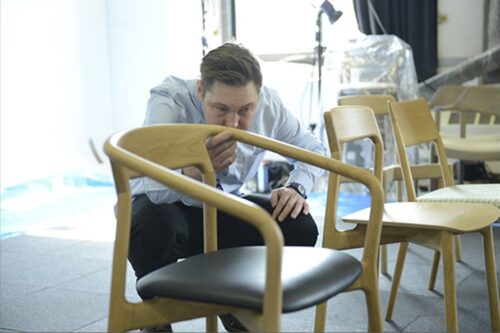 A designer is thoroughly checking the shape of the chair he designed.