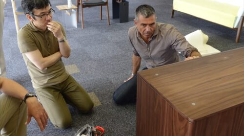 Two guys seem to be sunk in though watching a prototype cabinet