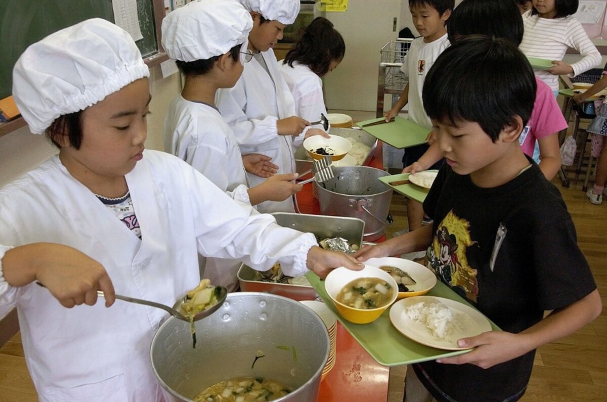 Elementary school kids are making a queue for a school lunch meal.