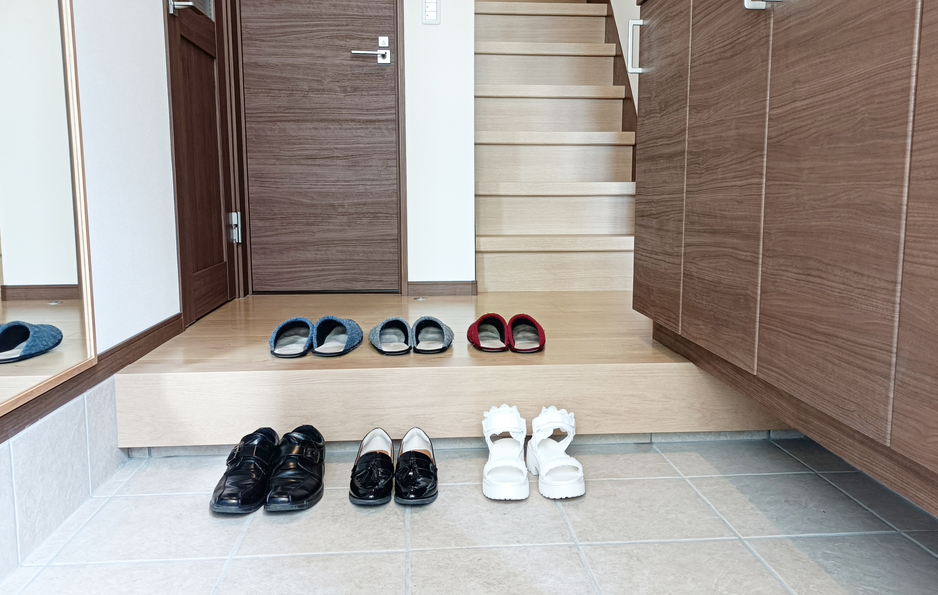 Some shoes are placed in an entrance porch. They are facing in the door direction.