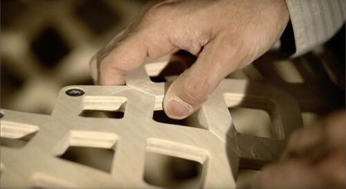 A craftsman's hand touching wooden grid-a part of furniture