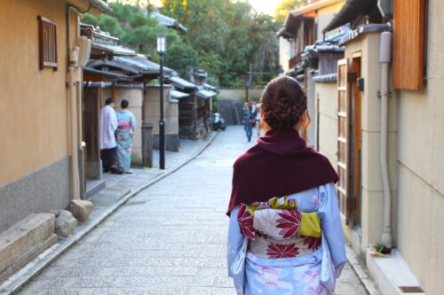 An old street somewhere in Kyoto with a back shot of a woman in kimono