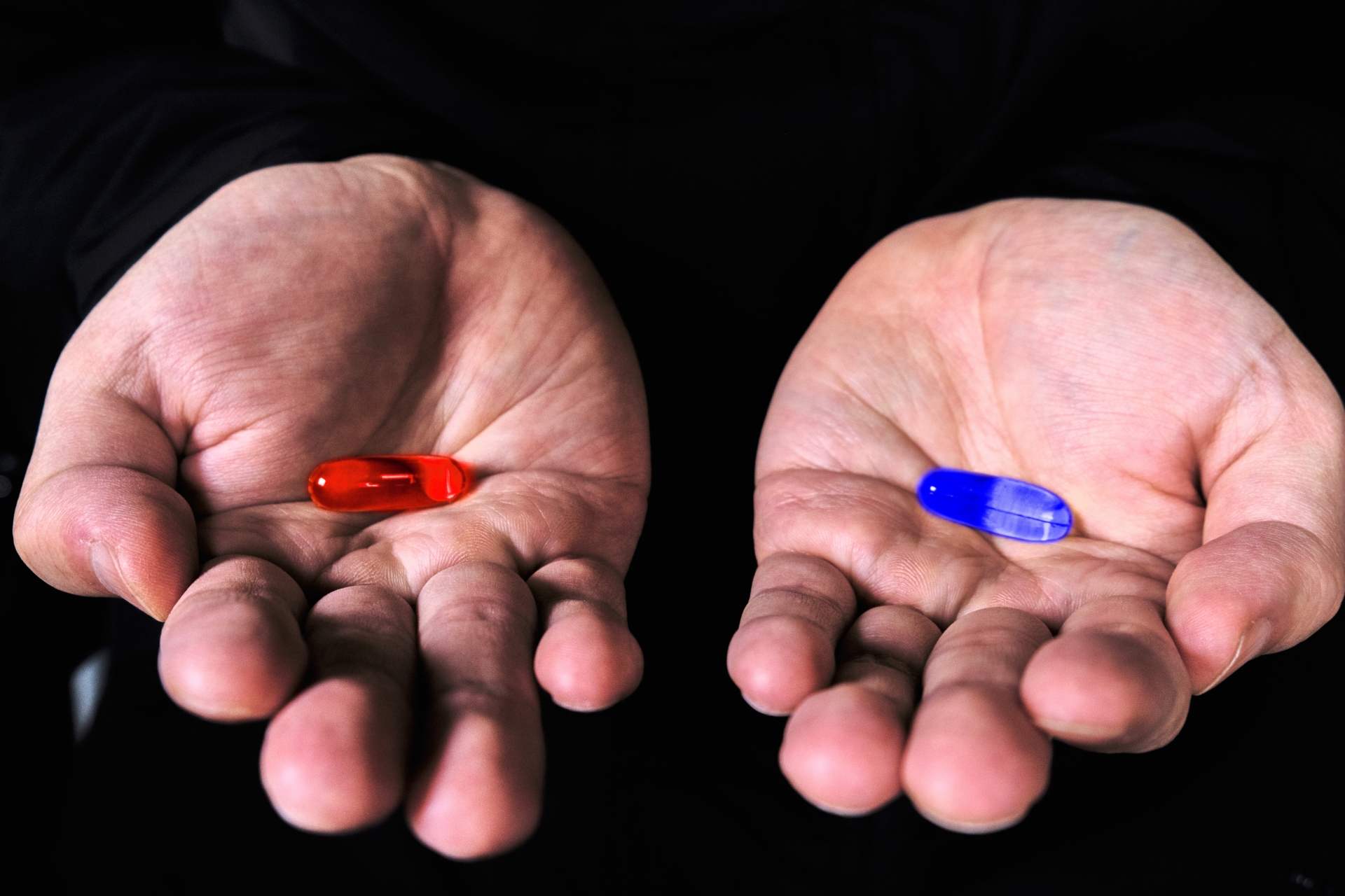 A red pill on the right palm; a blue pill on the left palm.