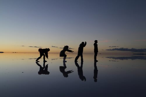 Four people are making a pose on the lake Uyuni.