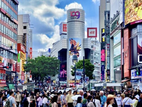 The downtown of Shibuya packed with many people under the blue sky