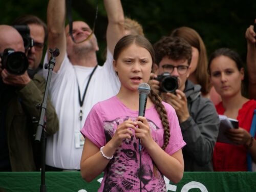 Greta Thunberg making a speech surrounded by media