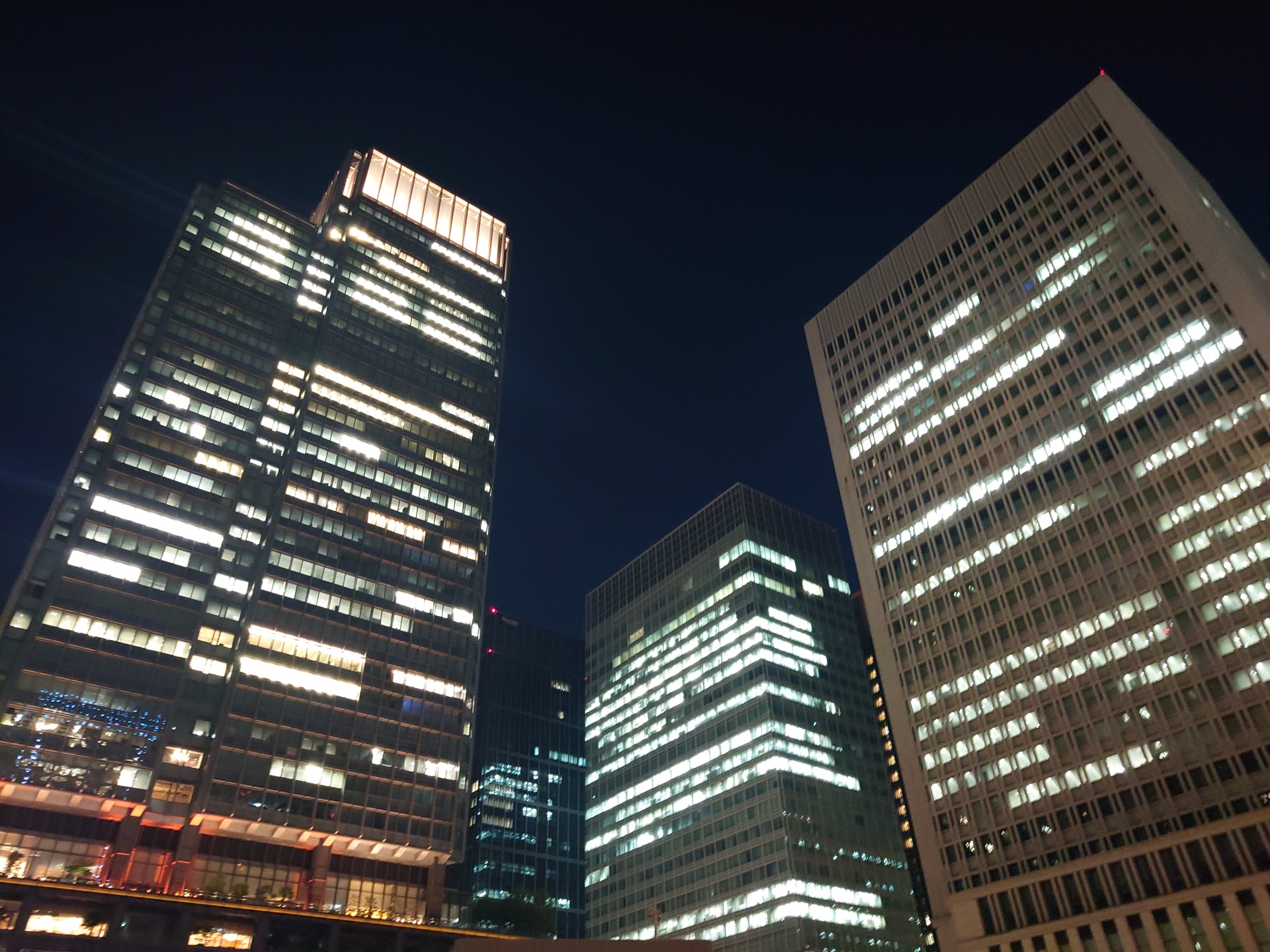 Office buildings somewhere in Tokyo at night, emitting light from their windows