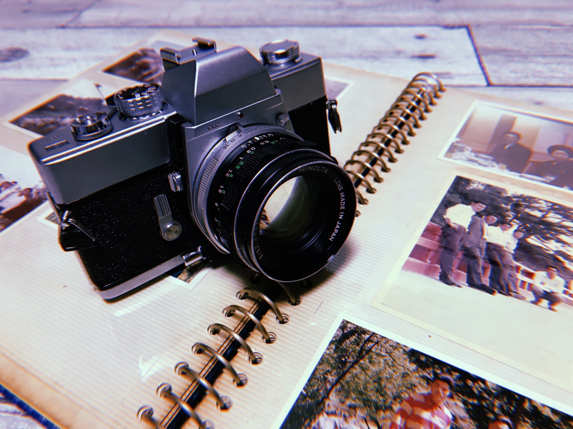 A classic camera is placed on an old photo album with black-white photos.