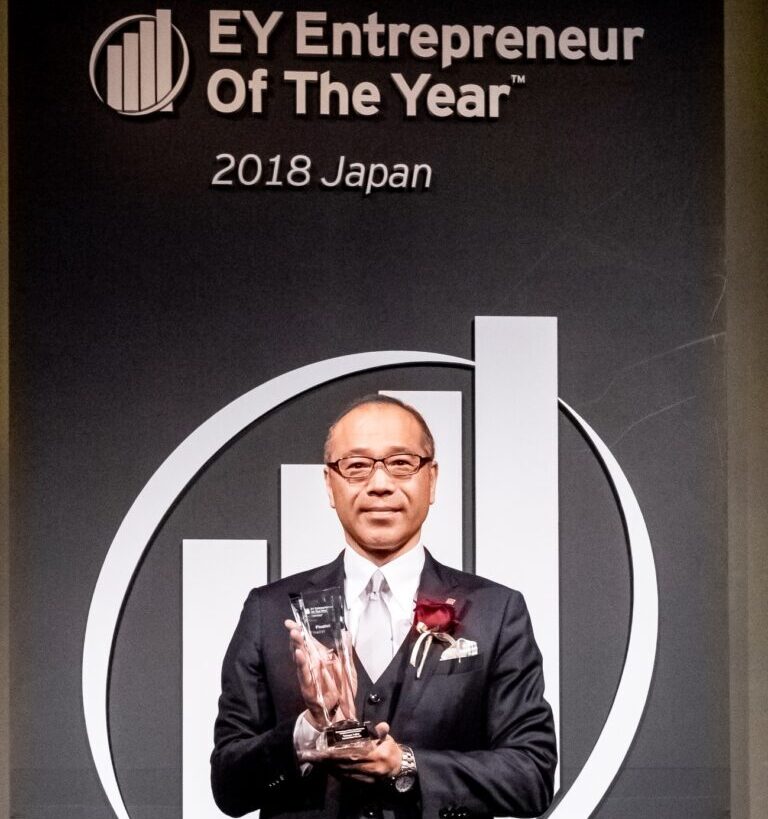 A guy in a black suit is holding a trophy.