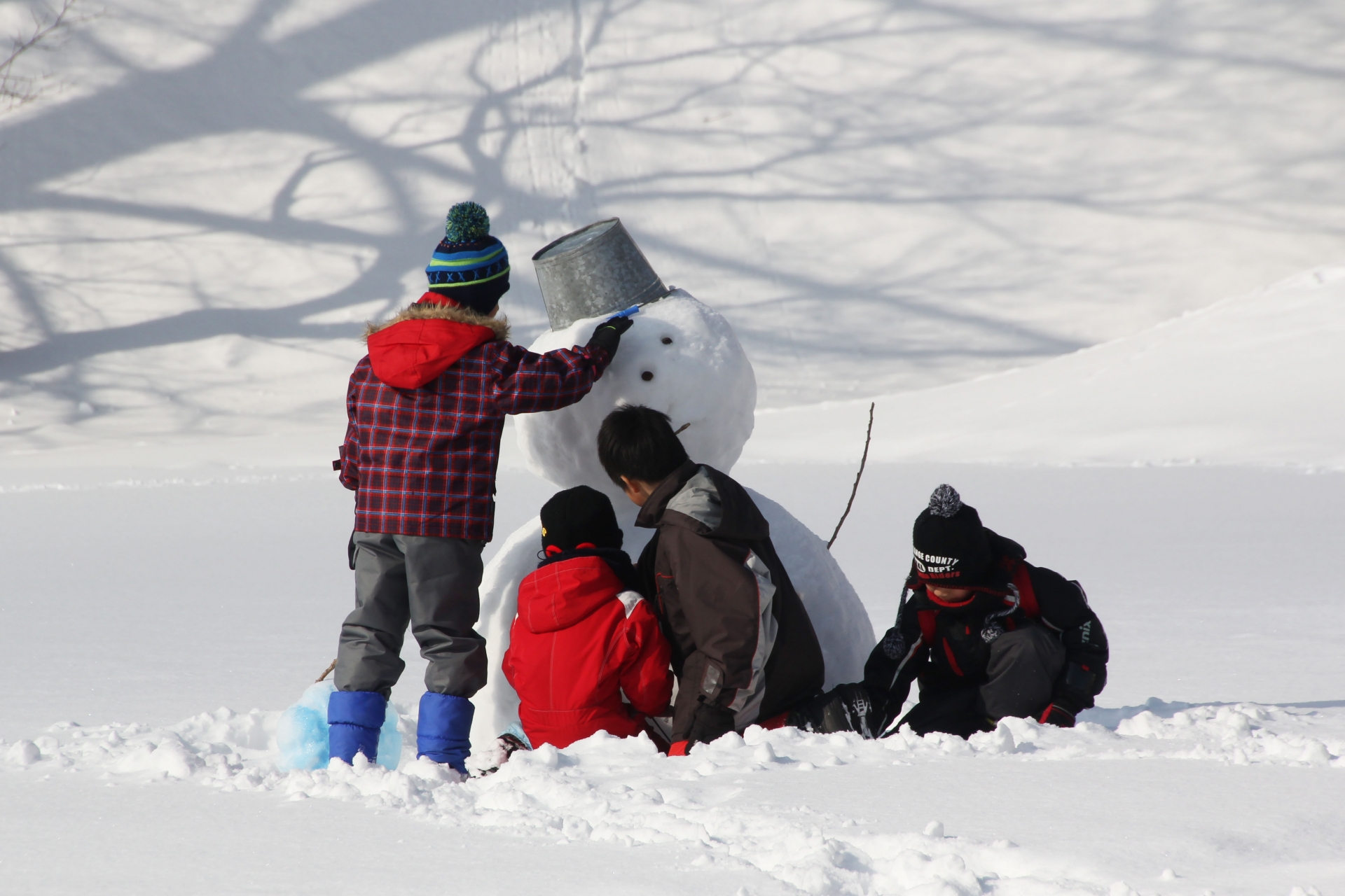 Some kids are making a snow man on the snow field.