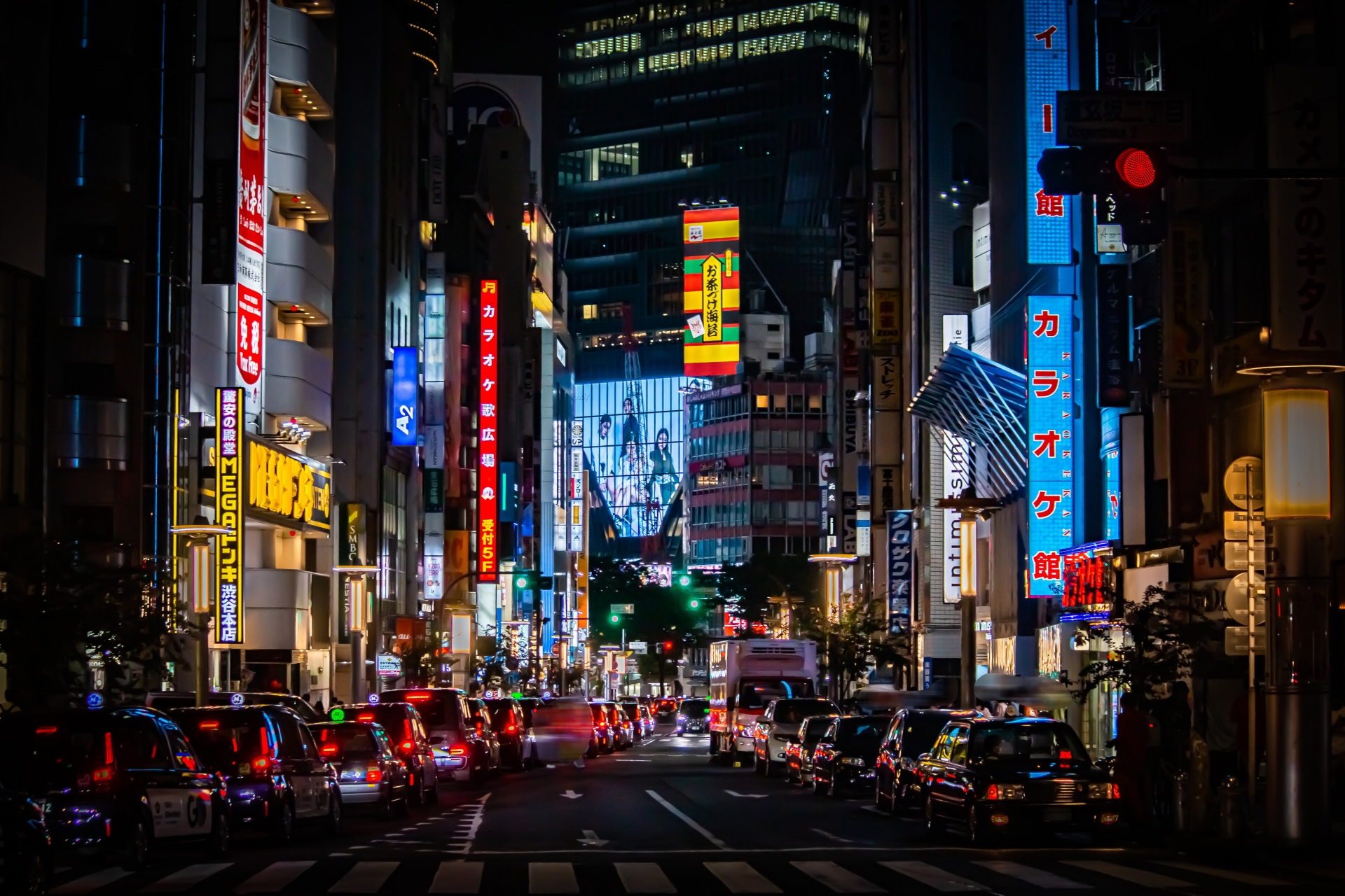 Some mid town in Tokyo at night where many cars make a long queue