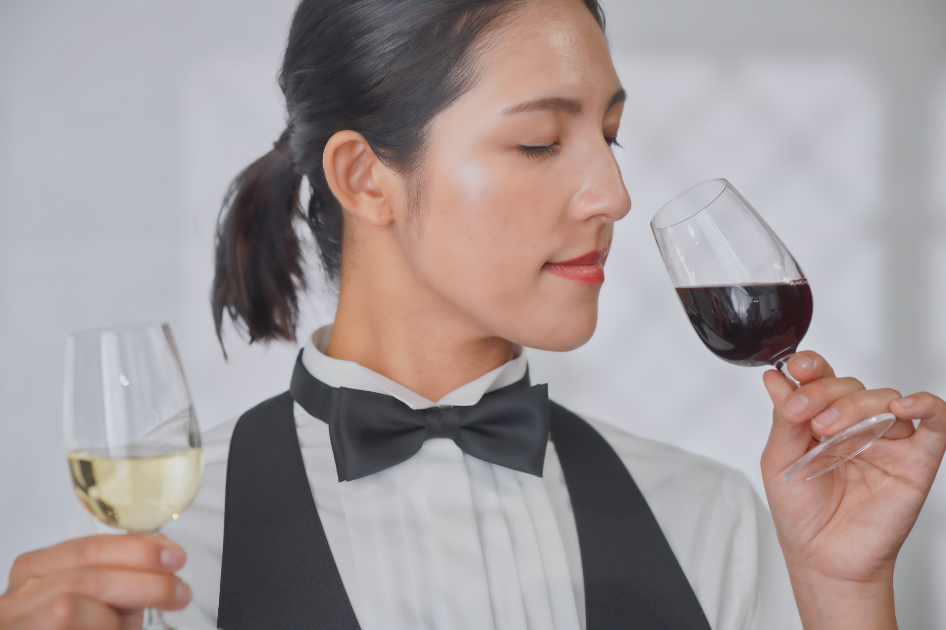 A female sommelier tasting two glasses of wine (red and white)