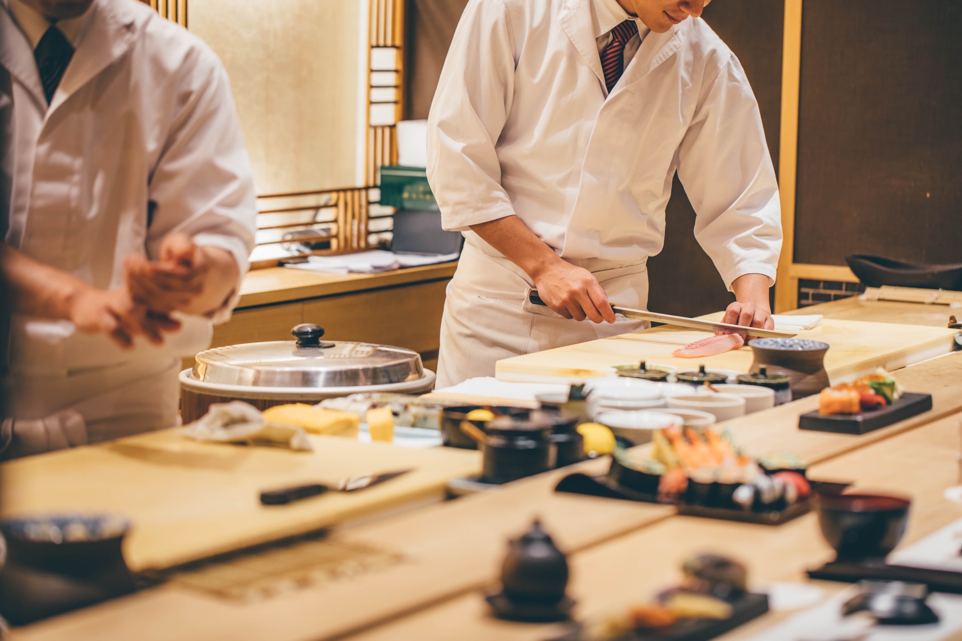 Sushi chefs are making sushi over the counter.