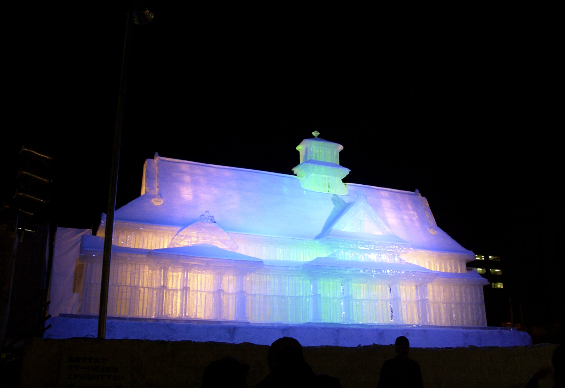 A snow statue of a building colorfully lit up at night