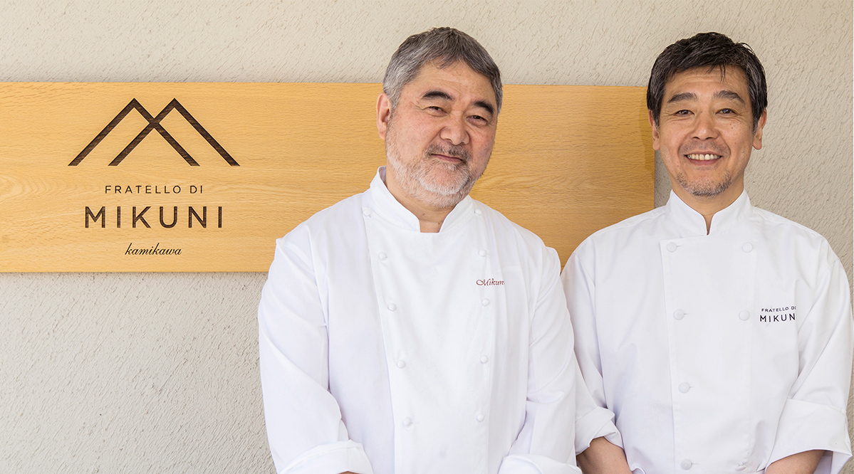 The chef Mikuni with his staff member in front of the sign of his restaurant in Hokkaido