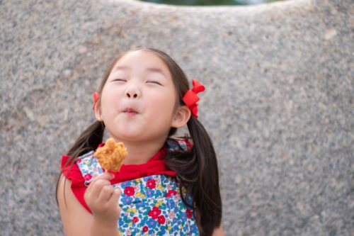 A girl with fried chicken in her right hand