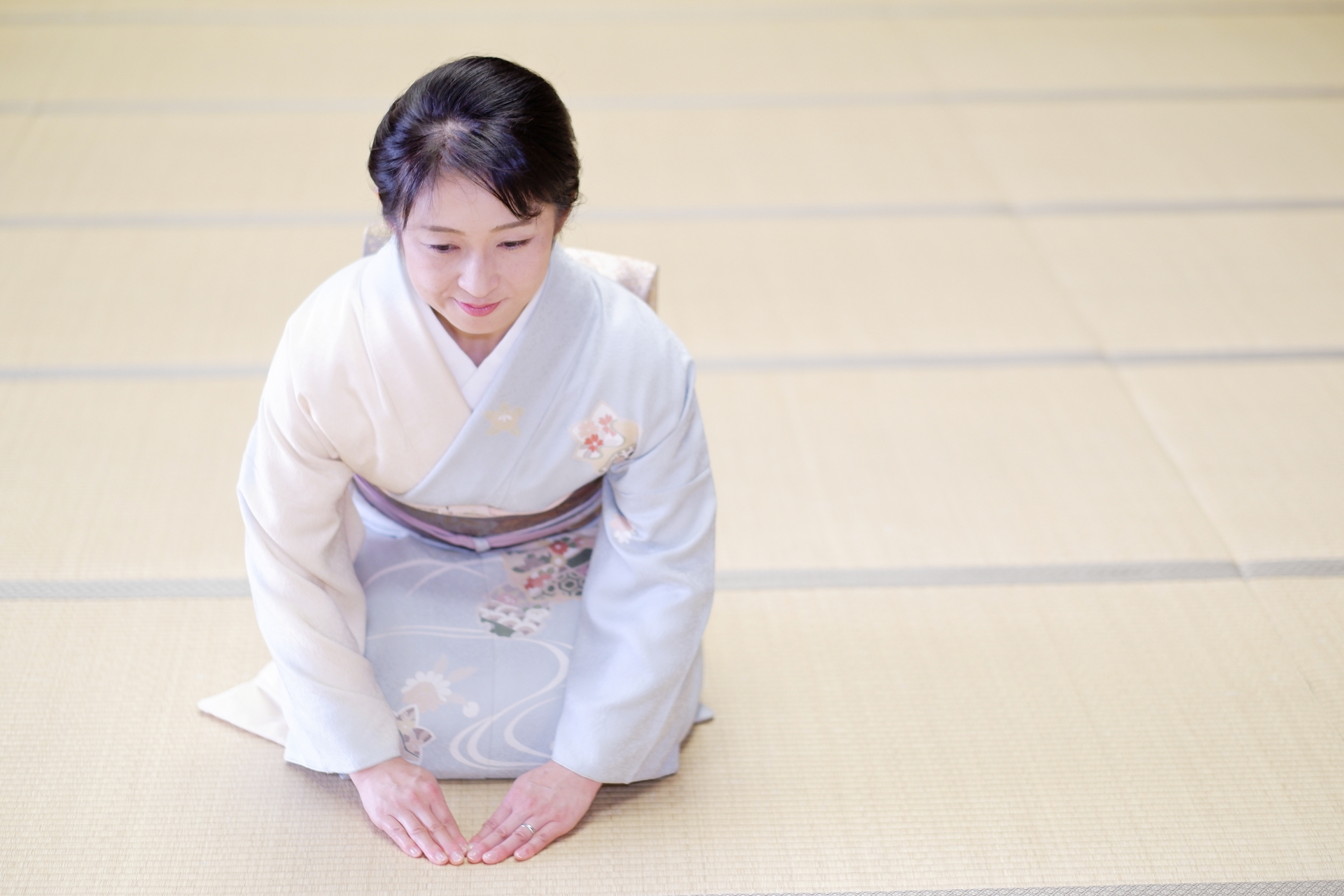 A woman sitting on tatami mats is about to bow.