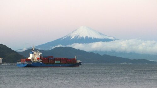 A container vessel is going on the sea, back of which there's Mt. Fuji.