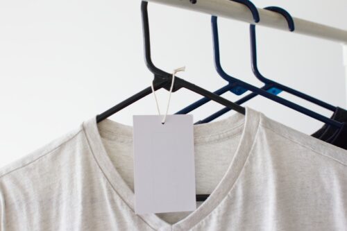 Some T-shirts are hung, and a blank tag is shown in the front shirt.