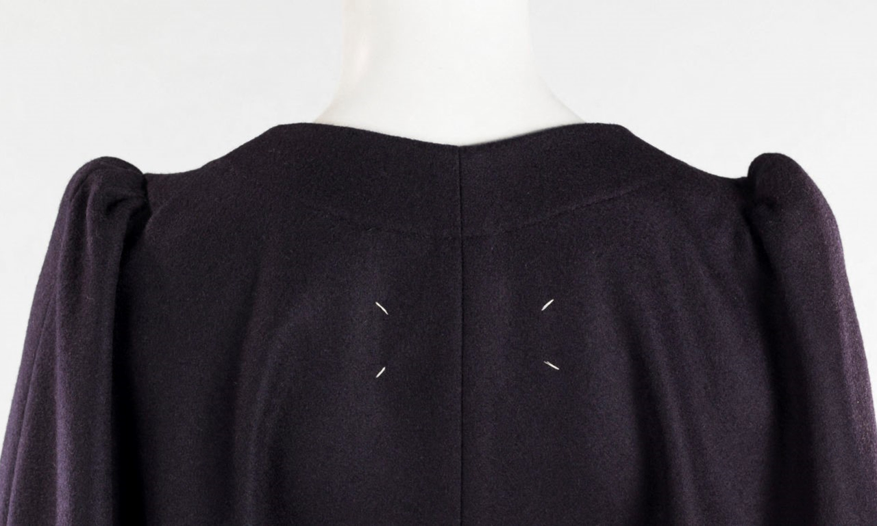 The backside of a black dress of Maison Margiela with four tacking stitches.