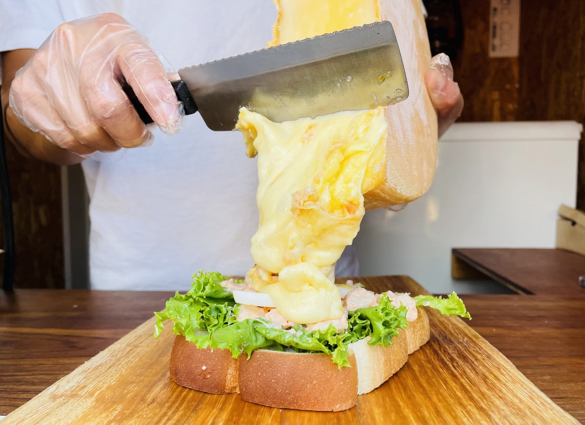 A lot of raclette cheese is poured on an open sandwich.