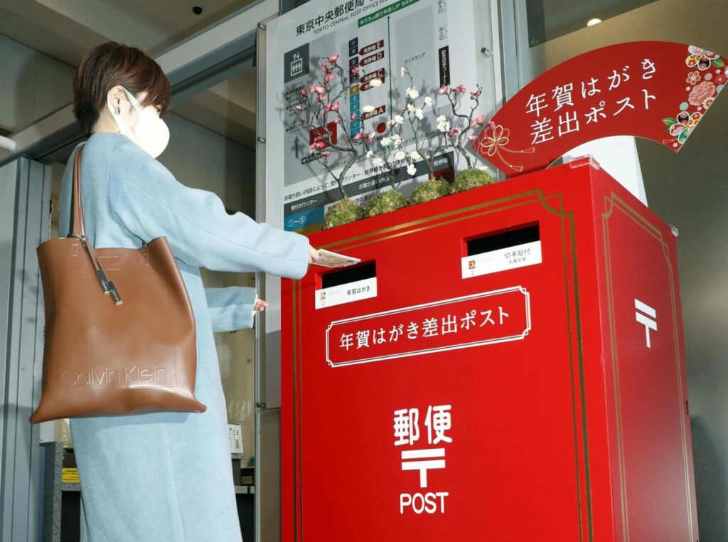 A woman is about to put some new-year post cards into a post.