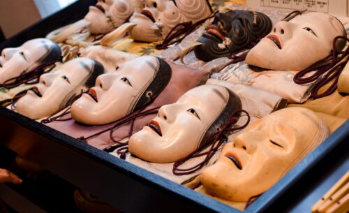 A variety of traditional Japanese Noh masks aligned neatly