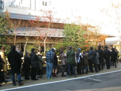 A long queue of people waiting for the opening of a soba noodle restaurant